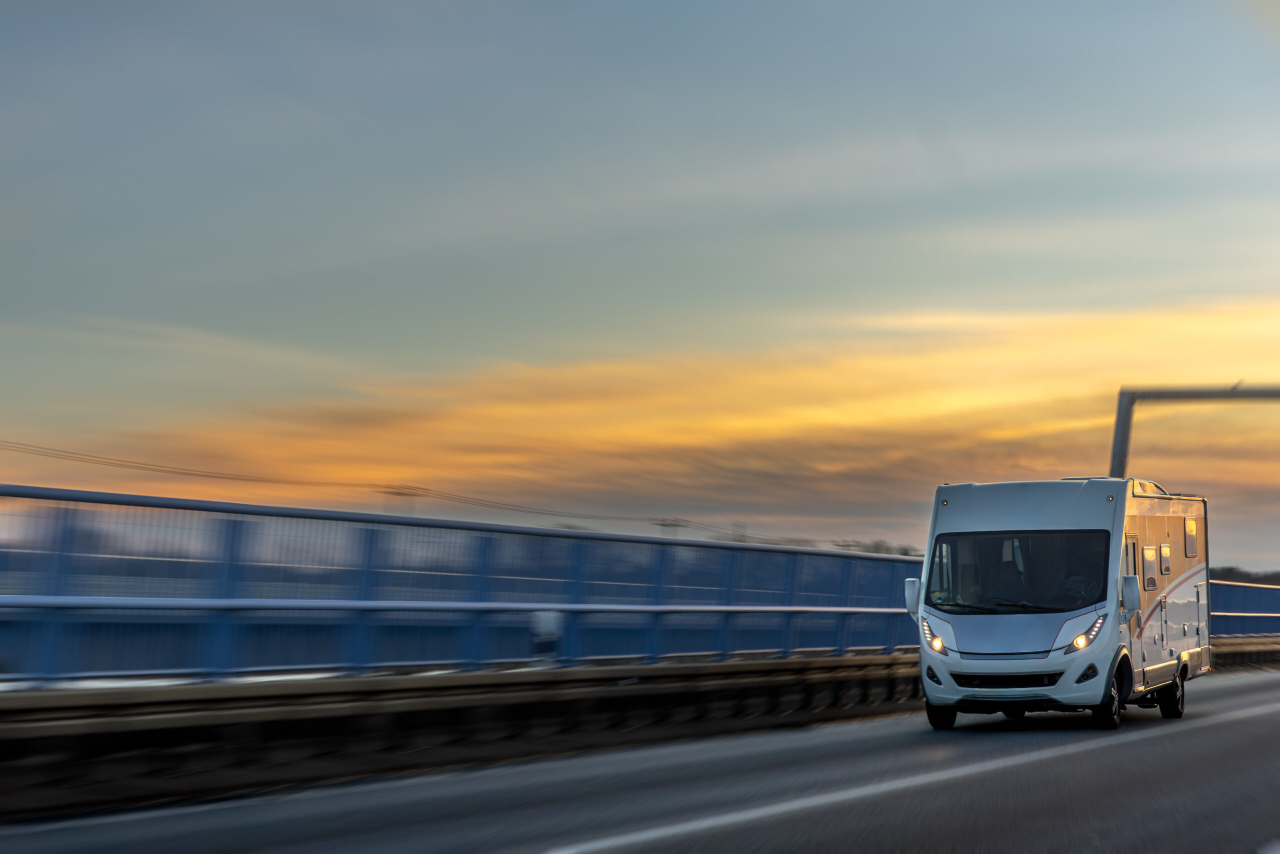 motorhome races across bridge at sunset. dream roadtrip.